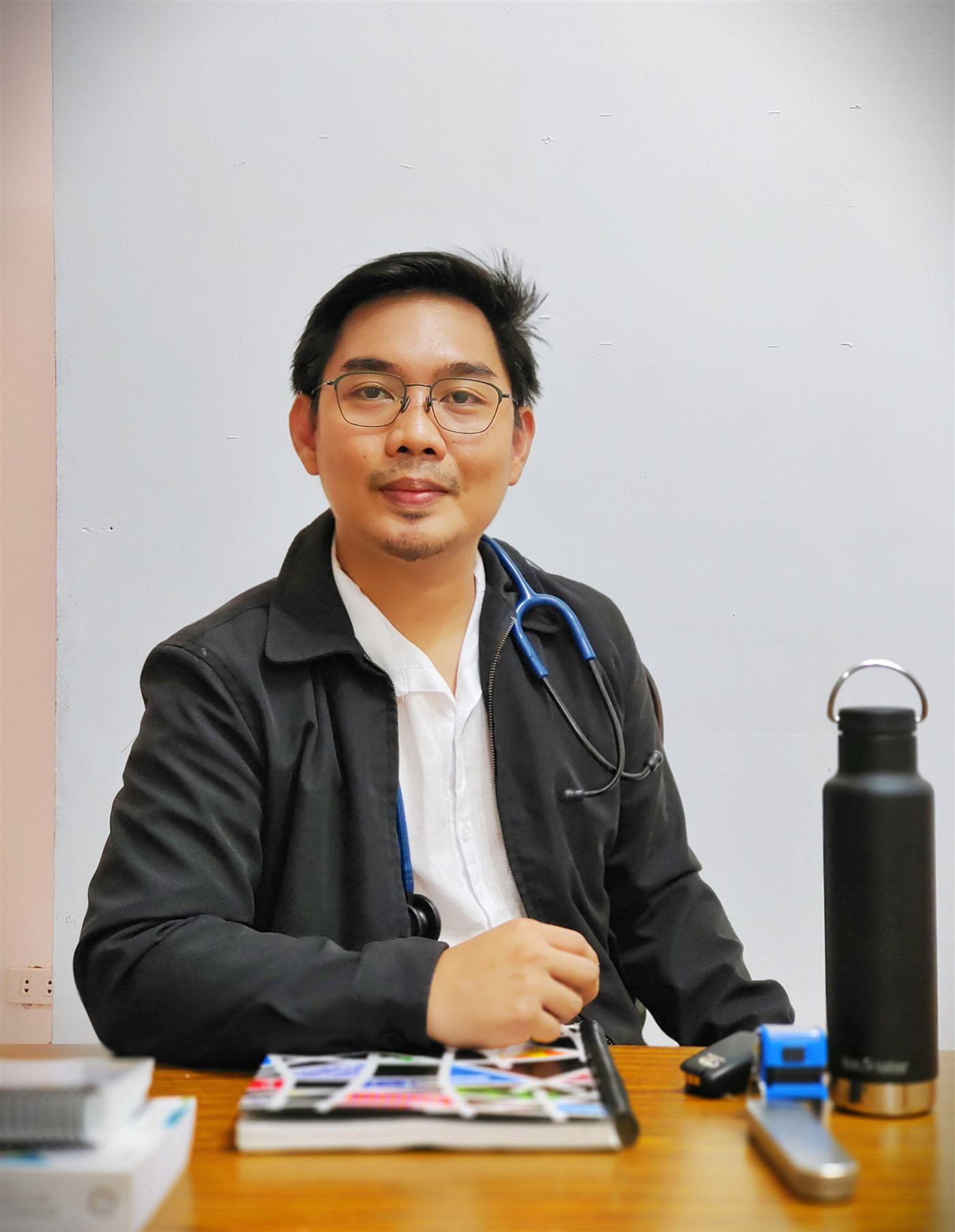 Dr. Franz Philip Joseph R. Ubaldo at his clinic desk, stethoscope around his neck