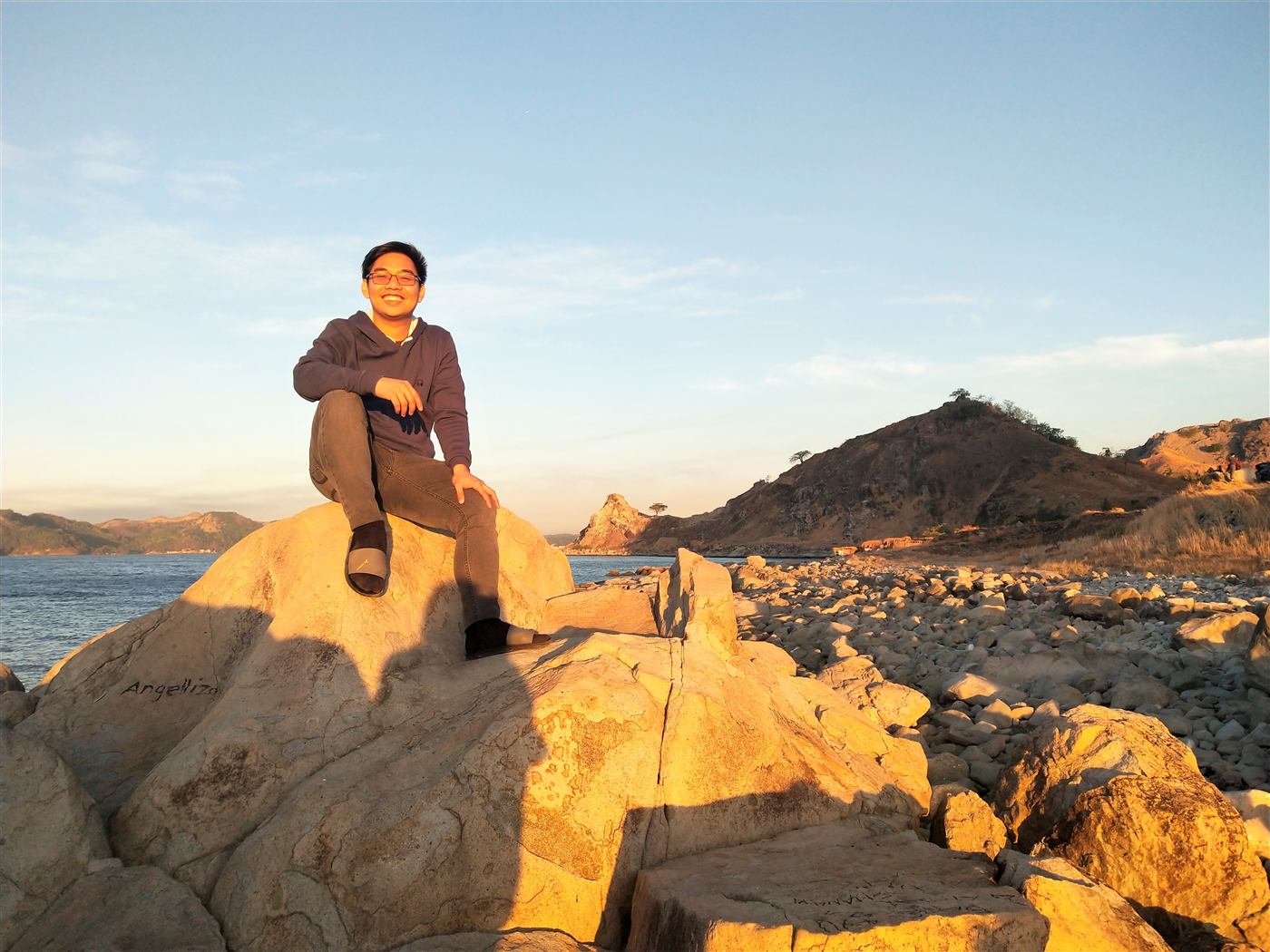 Jolas sitting on seaside boulders at golden hour